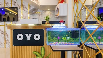 A reception desk with a sign reading 'OYO,' two aquariums, and a fan.