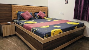 Una cama con una colcha estampada, un cabecero de madera y una mesita de noche con un teléfono y un control remoto.