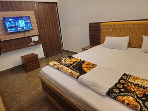 Habitación de hotel con cama, televisor montado en la pared y piso de madera.