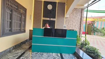 Un mostrador de recepción con un reloj y un letrero que dice 'UTKARSHA PALACE' en el vestíbulo de un hotel.