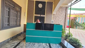 Un mostrador de recepción con un reloj y un letrero que dice 'UTKARSHA PALACE' en el vestíbulo de un hotel.