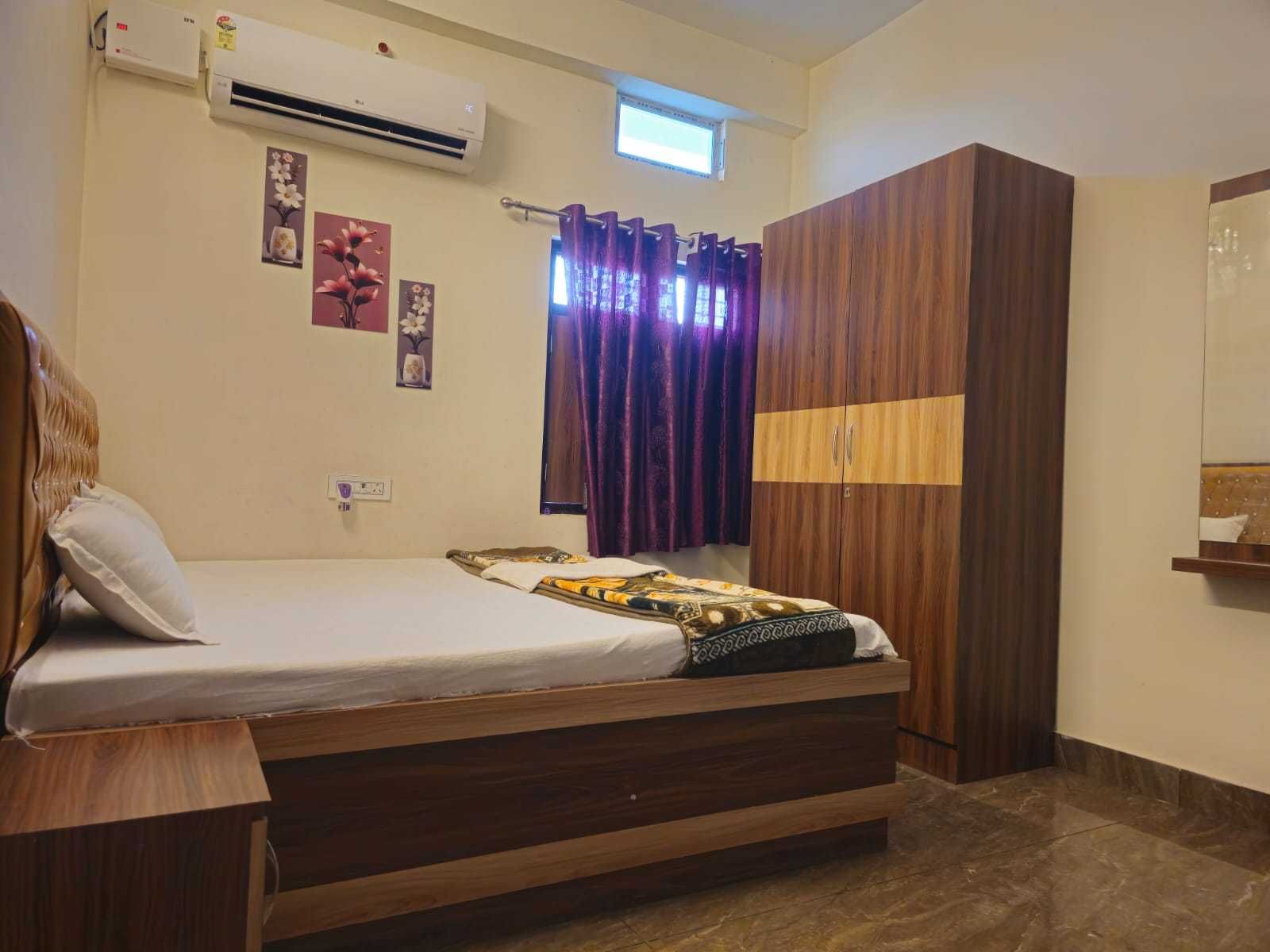 Un dormitorio con cama, armario, aire acondicionado y ventana con cortinas.