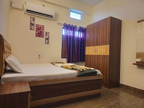 Un dormitorio con cama, armario, aire acondicionado y ventana con cortinas.