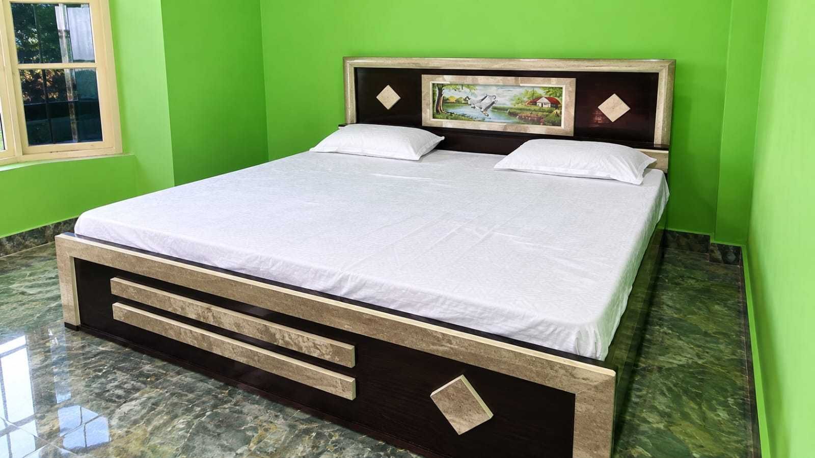 A bed with a headboard, a window, and a green wall.
