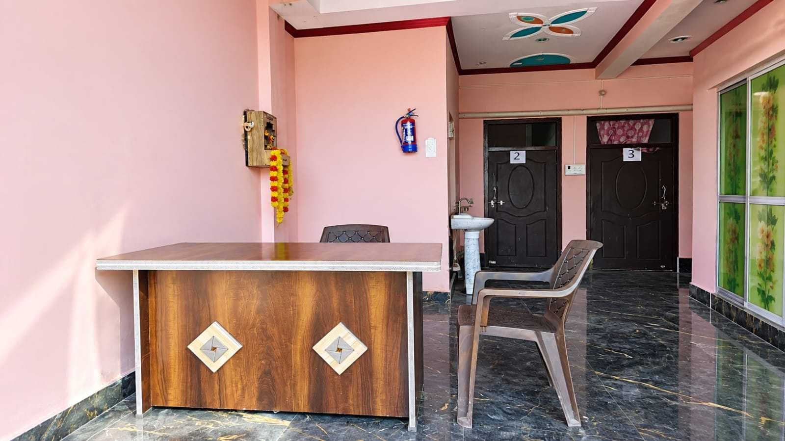 A reception desk with a wooden finish and two diamond-shaped cutouts, a plastic chair, a fire extinguisher, and a door with the number 3.