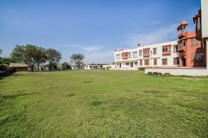 A spacious grassy courtyard with a building featuring multiple windows and a traditional architectural style.
