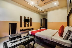 A hotel room with a bed, a flat-screen TV, a small table, and a ceiling fan. - Hotel O Hadoti Resort (Bhilwara)