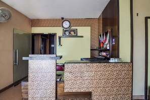 A reception area with a clock, a sign indicating a bathroom, and a counter with a patterned design. - Hotel O Hadoti Resort (Bhilwara)