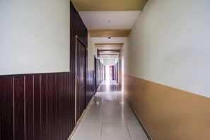 A long, narrow hallway with a wooden panel on one side and a plain wall on the other.