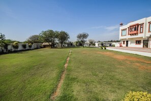 A well-maintained grassy lawn with a clear path, surrounded by a low wall and trees.