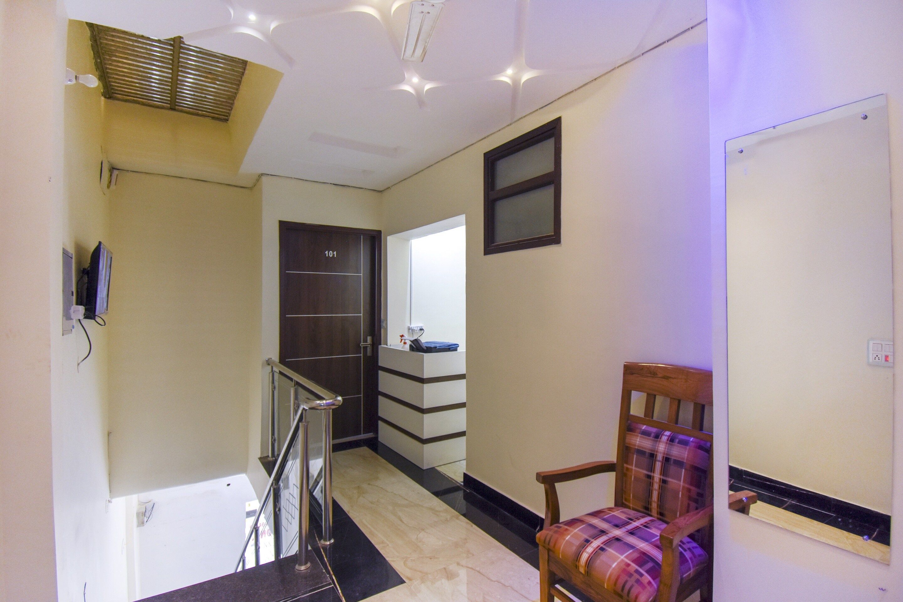 A hallway with a wooden chair, a door labeled '101', and a staircase.