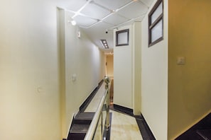 A hallway with a handrail, a ceiling with recessed lighting, and a door at the end.