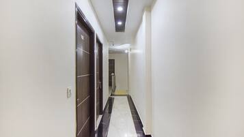 A corridor with a tiled floor, a door on the left, and a light fixture on the ceiling.