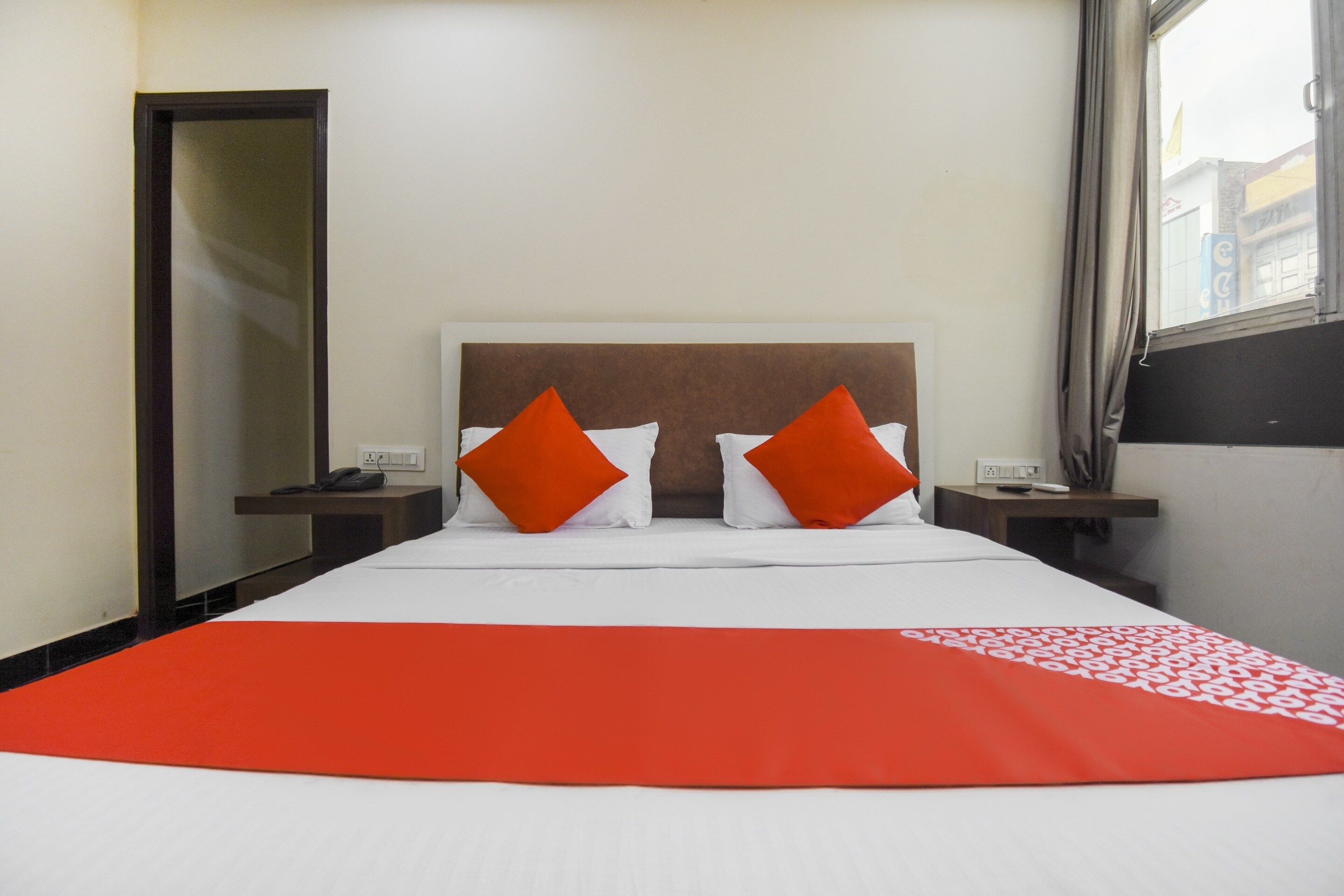 Ein Hotelzimmer mit einem Bett, zwei Nachttischen, einem Telefon und einem Vorhangfenster.