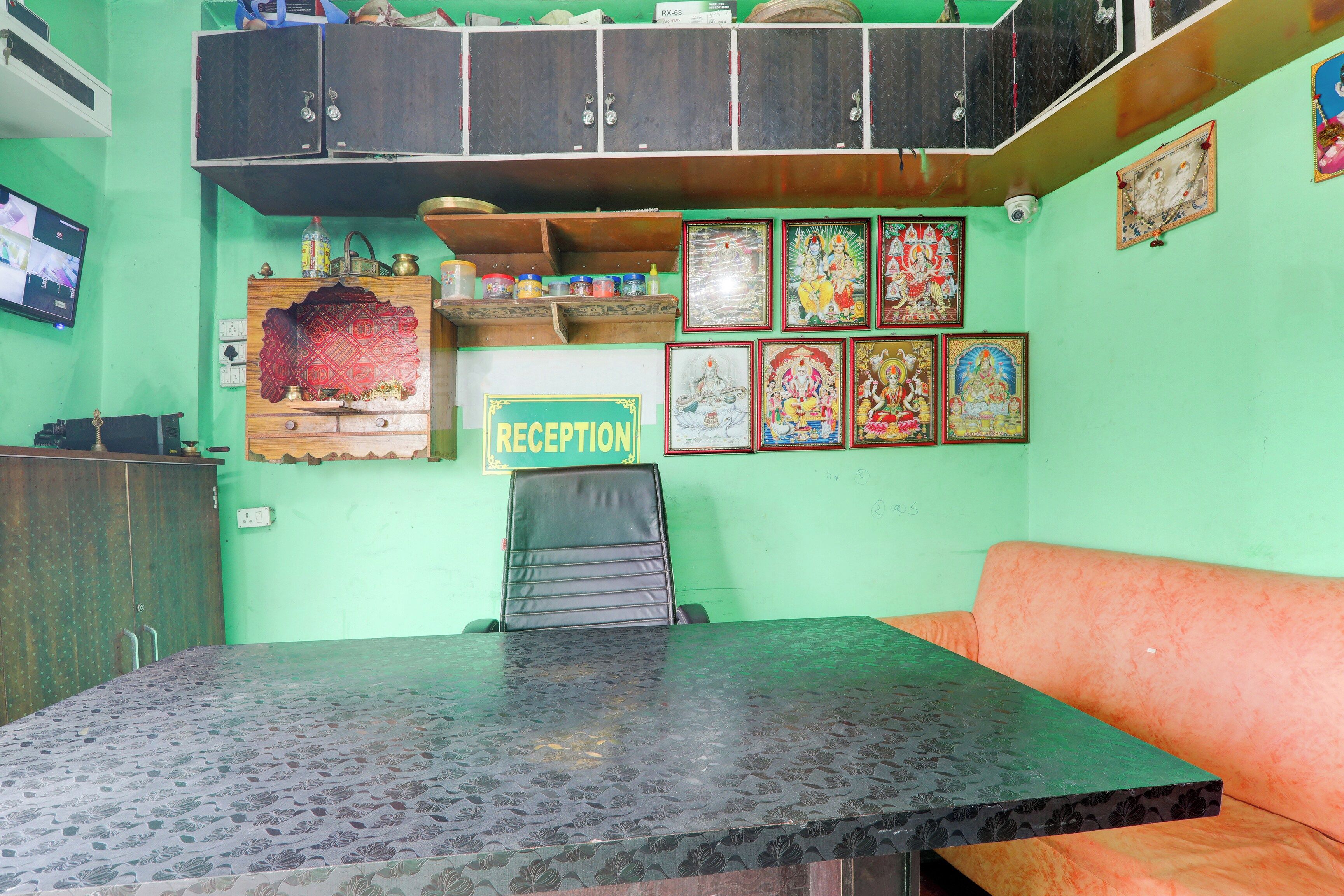 Una zona d'entrada amb una taula d'informació, un sofà i una paret decorada amb quadres religiosos.