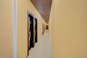 Un largo y estrecho pasillo de hotel, con puertas a un lado y una pared lisa al otro.