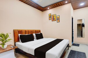Une chambre d’hôtel avec un lit, une table de chevet ornée d’une plante et des œuvres d’art accrochées au mur.