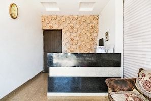 A reception area with a patterned wall, a reception desk, a clock, and a sofa.