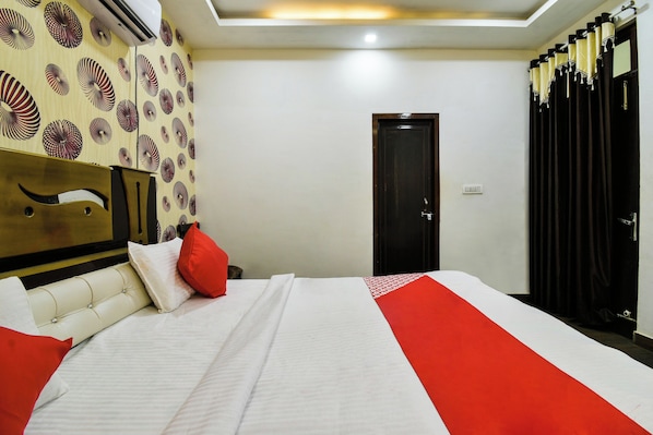 A hotel room with a bed, a headboard, a door, and curtains.