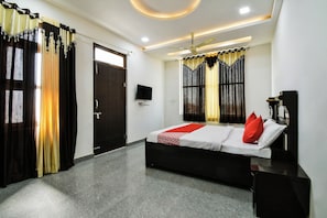 A bedroom with a bed, a television, and curtains. - Hotel O Apple Inn (Bharatpur)