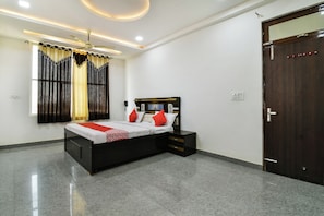 A modern bedroom with a bed, bedside tables, a wardrobe, and a window with curtains. - Hotel O Apple Inn (Bharatpur)