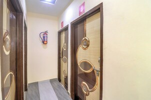 Um corredor com três portas, cada uma com um design único, e um extintor fixado na parede.