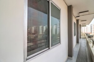 Um corredor com grandes janelas, teto com iluminação embutida e vista para edifícios lá fora.