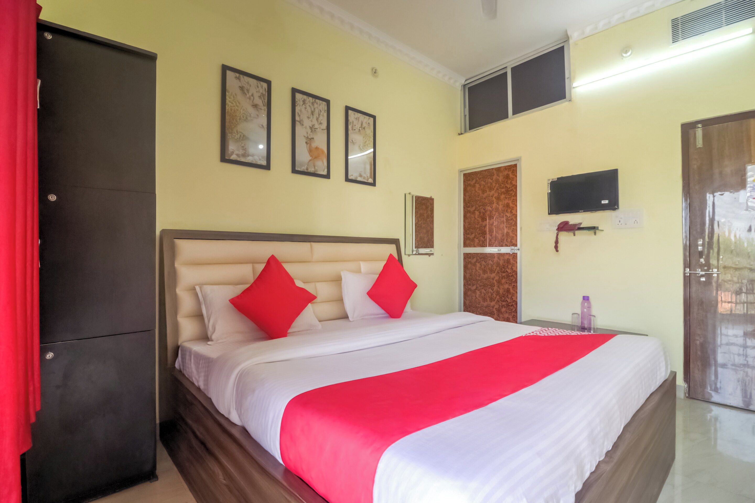 Habitación de hotel con cama, armario, televisión y una obra de arte en la pared.