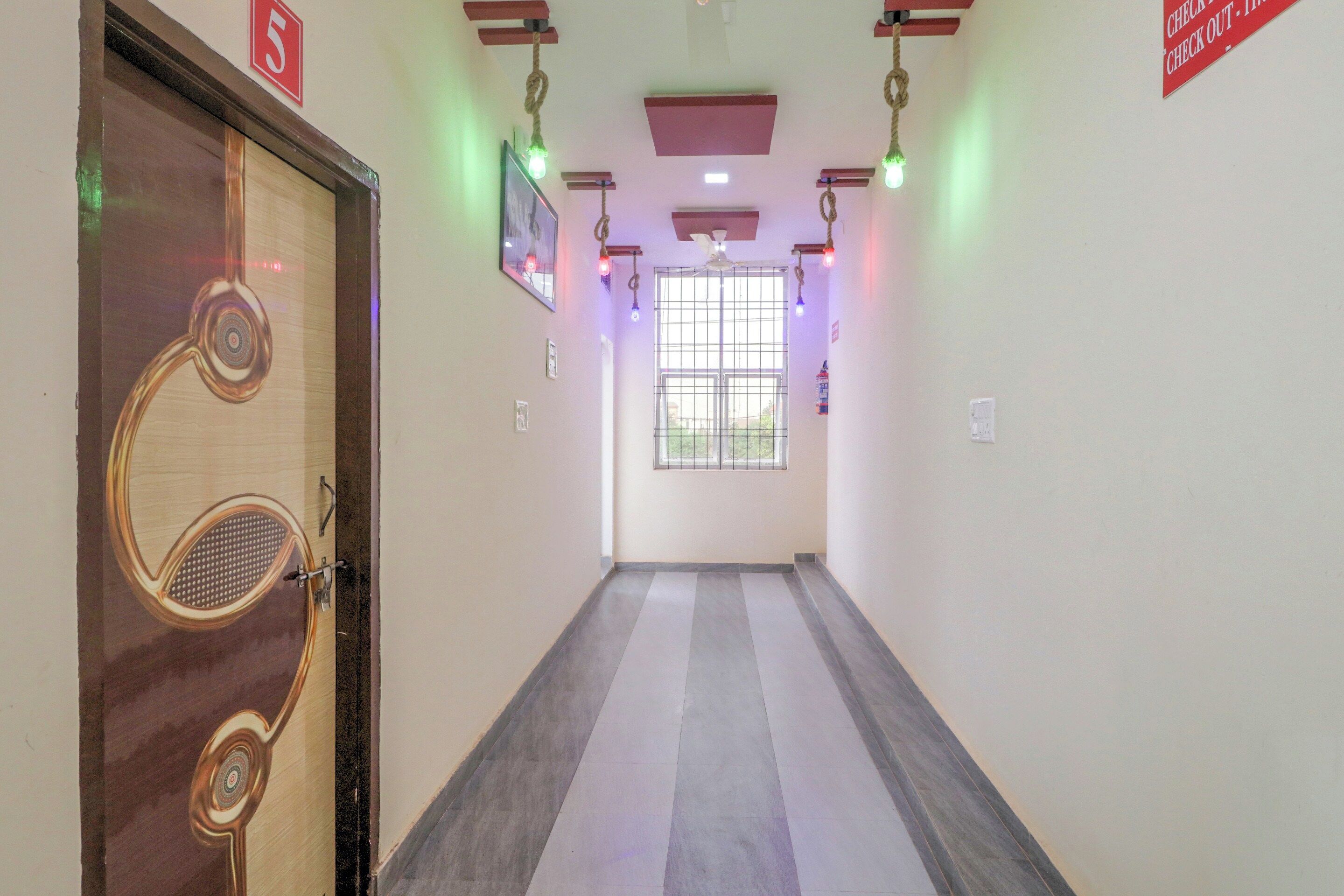 A hallway with a wooden door, a ceiling fan, and a window with metal bars.