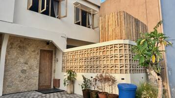 A modern building with a stone facade, a wooden door, and a balcony with potted plants.