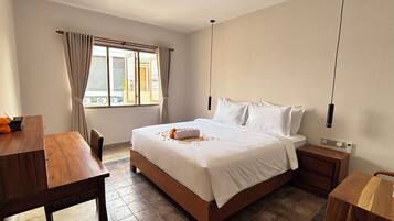 A hotel room with a bed, bedside table, and a window with curtains.