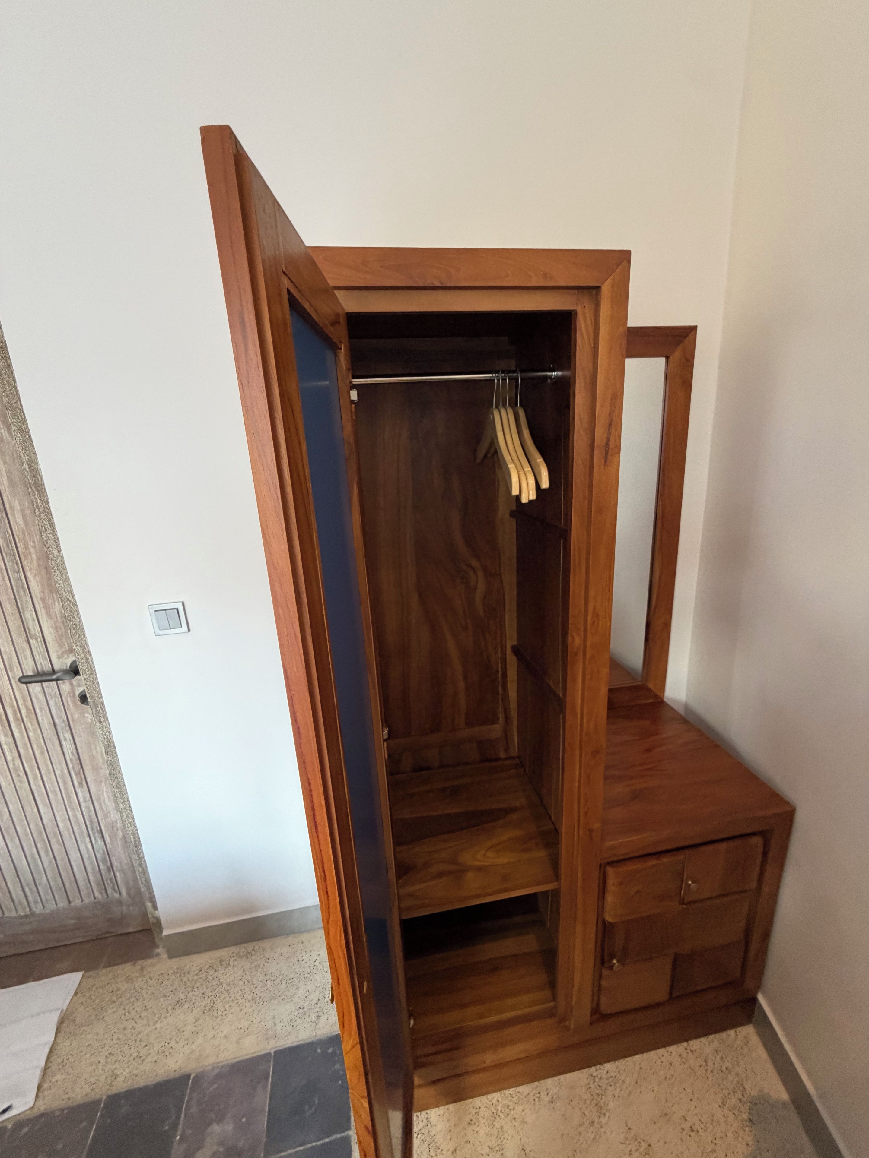 Een houten kast met een kledingroede en een klein ladeblok.