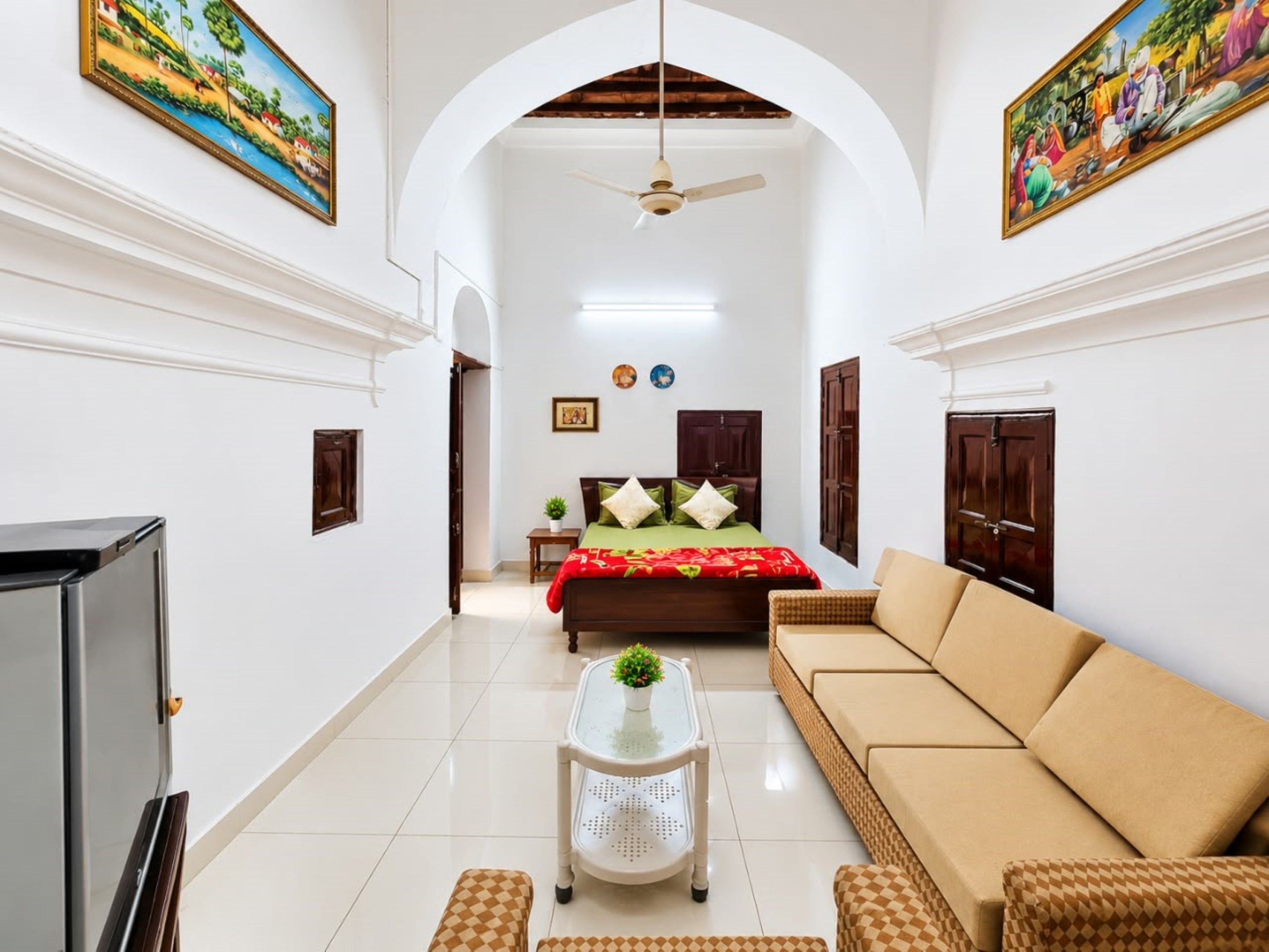 A spacious living area with a sofa, a television, and a ceiling fan.