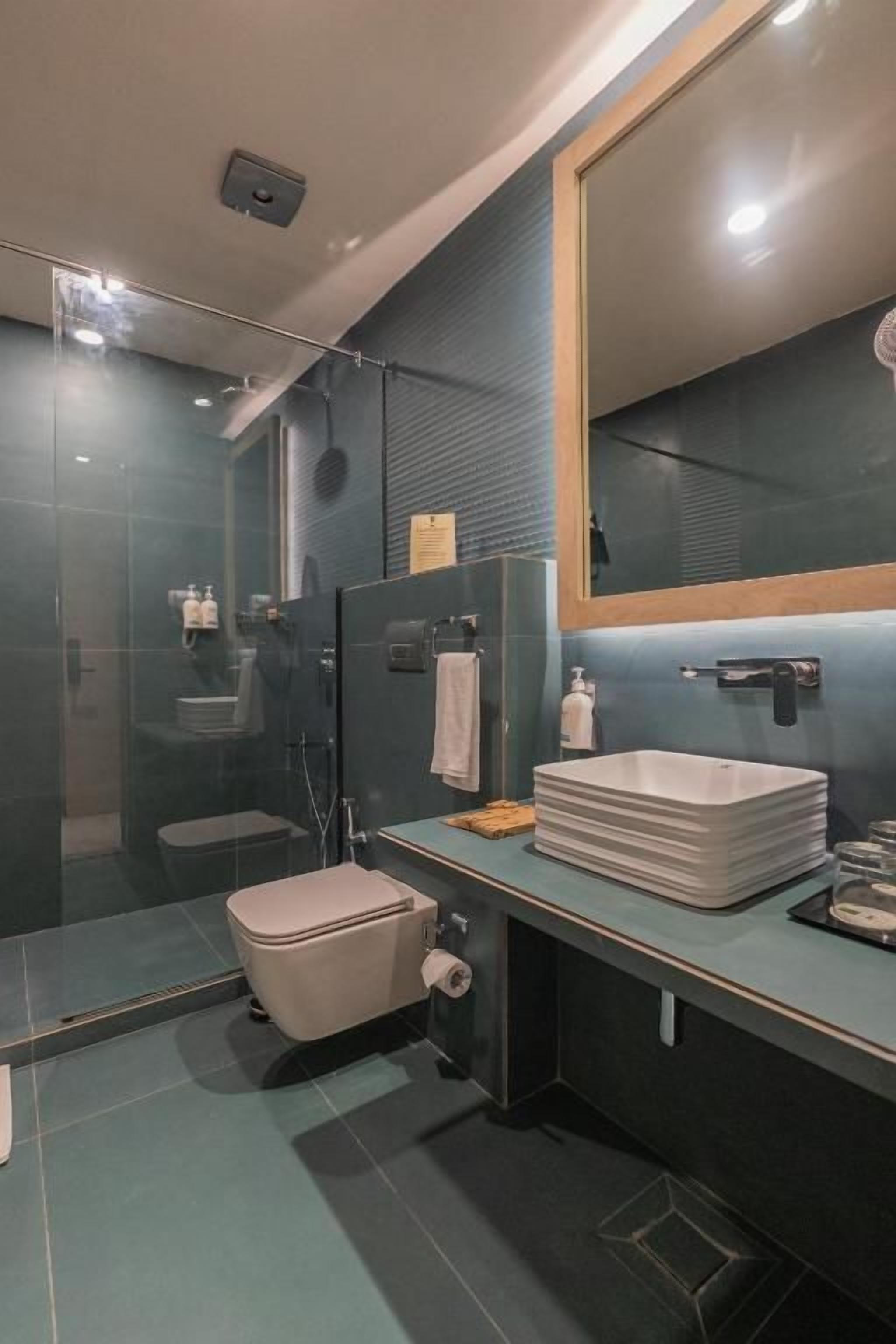 A modern bathroom with a glass shower enclosure, a toilet, and a sink with a mirror above it.