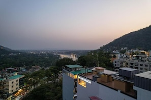 Un edificio de gran altura con terraza en la azotea, un letrero que indica un restaurante y vistas de un valle con un puente a lo lejos.