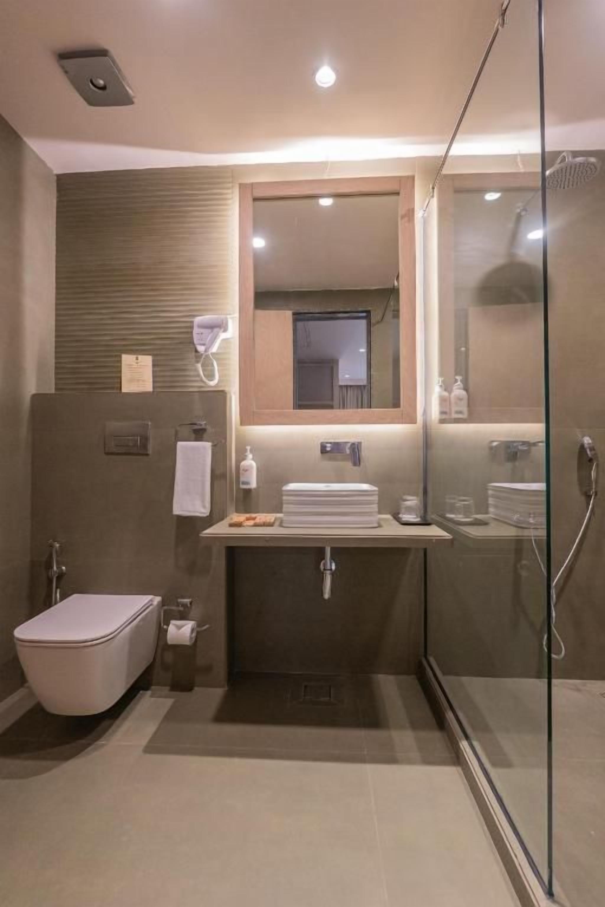 A modern bathroom with a glass shower enclosure, a toilet, a sink with a mirror, and a towel rack.