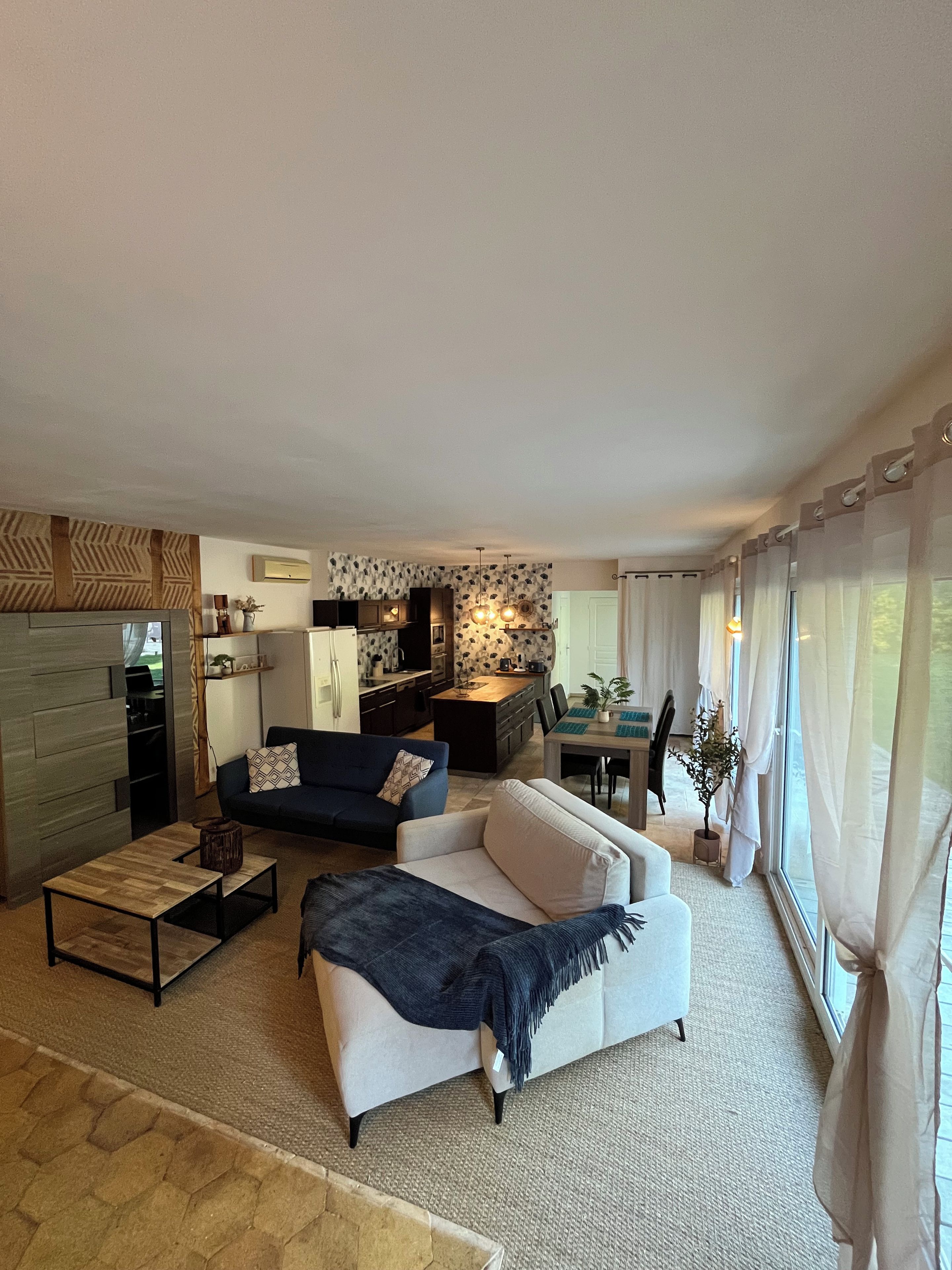 A modern living room with a sofa, a coffee table, and a dining area with a table and chairs.