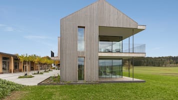 Ein modernes, zweistöckiges Gebäude mit geneigtem Dach, großen Fenstern und einem Balkon.