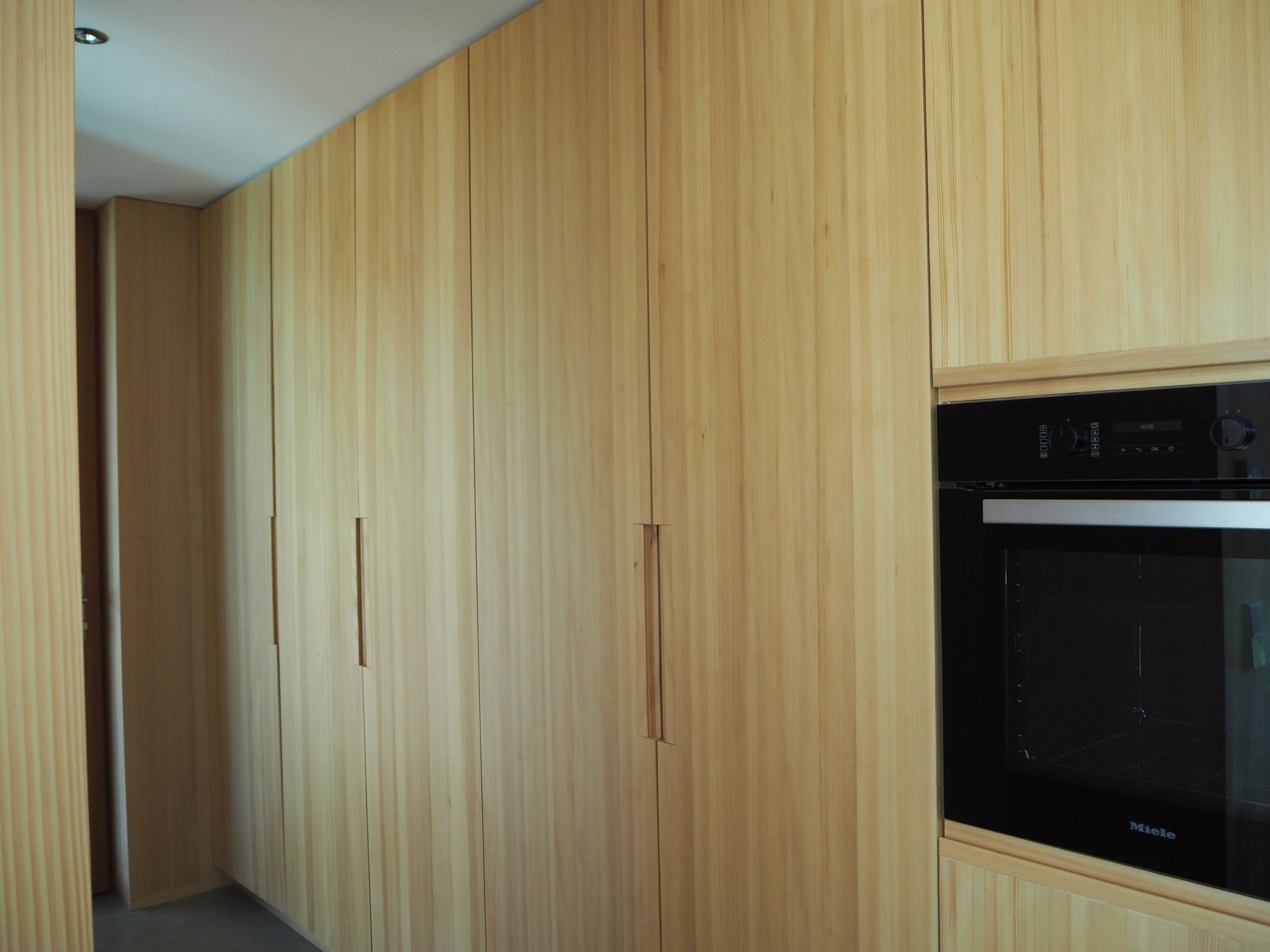 Een keuken met houten kastjes en een zwarte oven.