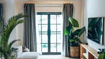 Een moderne woonkamer met een bank, een salontafel en grote potplanten.