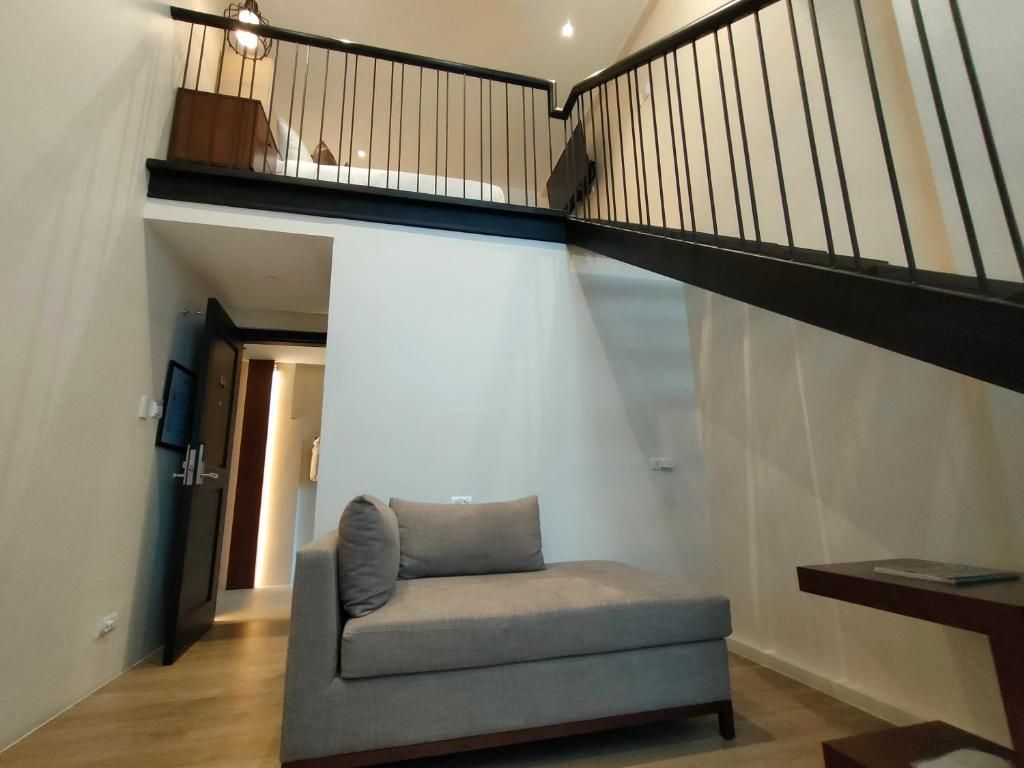 A staircase with a black railing and a grey sofa in a hallway.