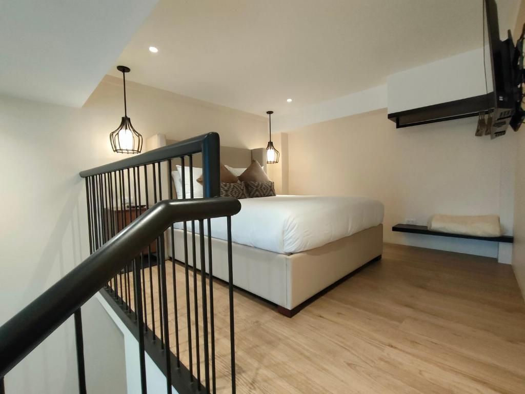 A bedroom with a bed, a staircase, and a hanging light fixture.