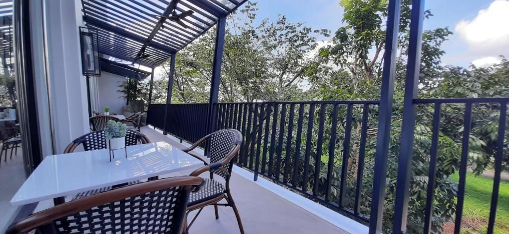 A balcony with a table and chairs, a metal railing, and a view of greenery.