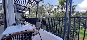 A balcony with a table and chairs, a metal railing, and a view of greenery. - Girasol Tagaytay (Alfonso)