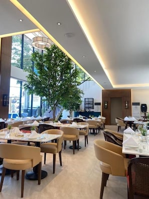 A modern restaurant interior with multiple dining tables, chairs, and a central tree. - Girasol Tagaytay (Alfonso)