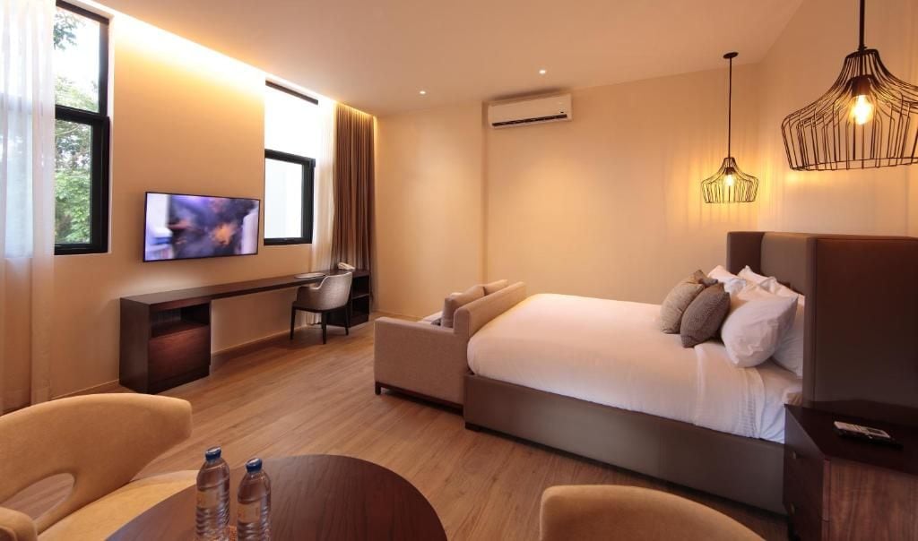 Una habitación de hotel moderna con cama, escritorio, silla y televisor.