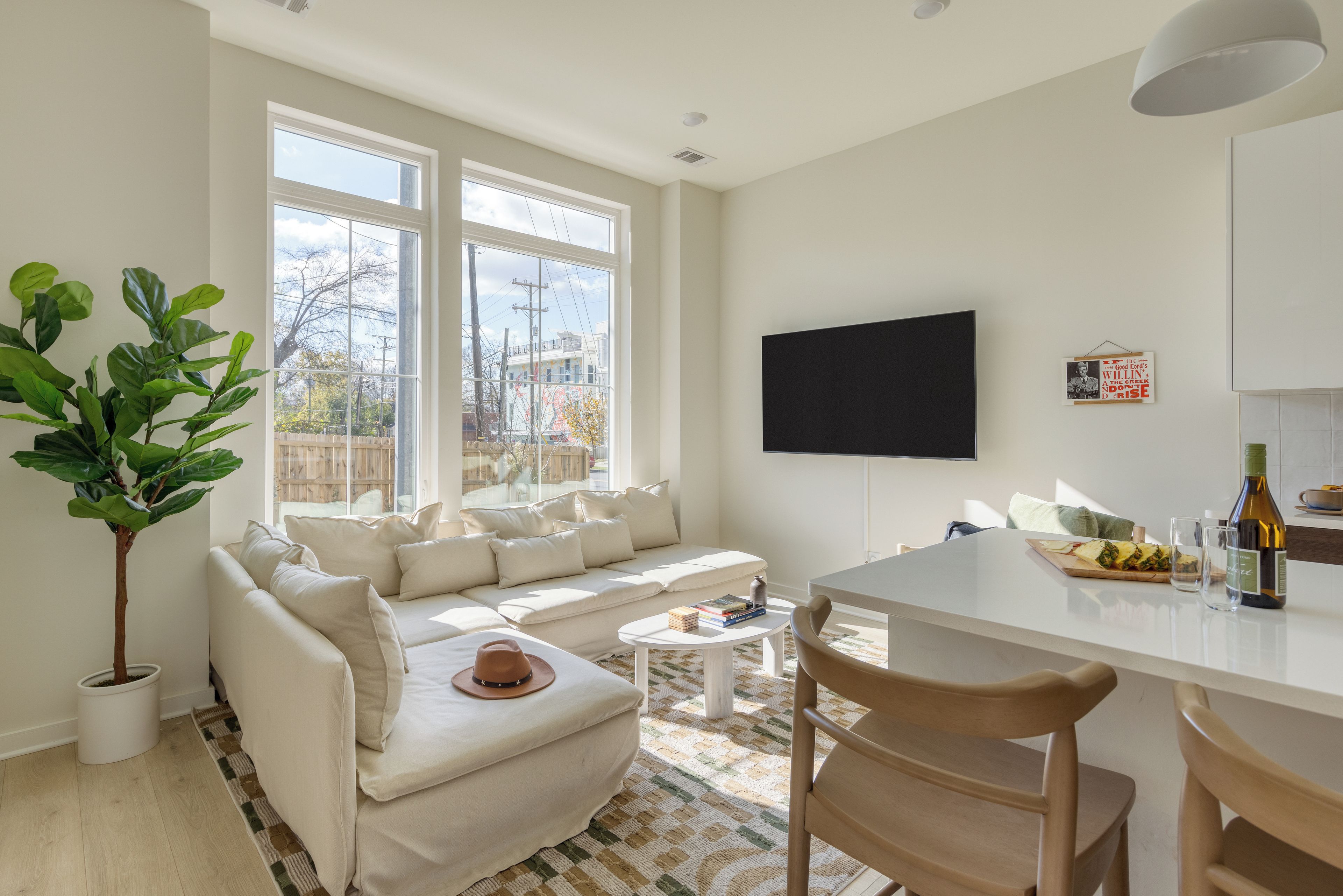 Un salon moderne avec un canapé blanc, une table basse et un coin repas comprenant une table et des chaises blanches.