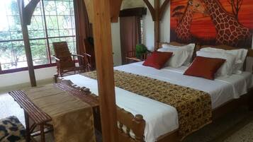 A room with a bed, a wooden bench, a table, and a giraffe mural on the wall.