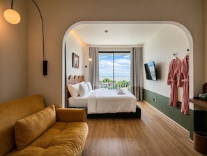 Una habitación de hotel con cama, sofá, televisión y vistas al exterior.