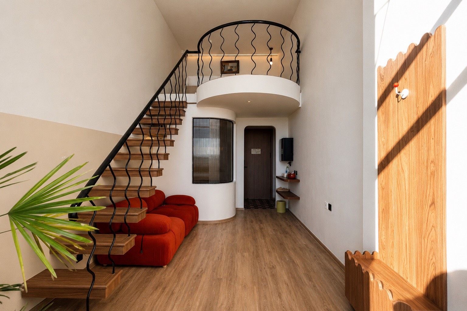 Un interior moderno con una escalera de caracol, un sofá rojo y suelo de madera.